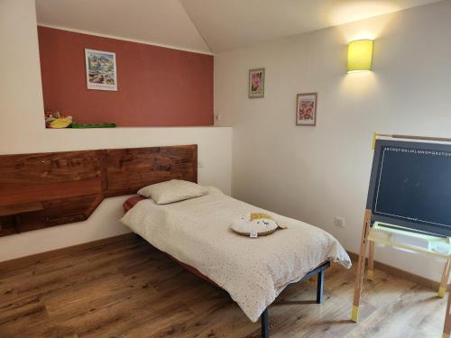 a small bedroom with a bed and a flat screen tv at Le Gîte du Moulin in Saint-Maigrin