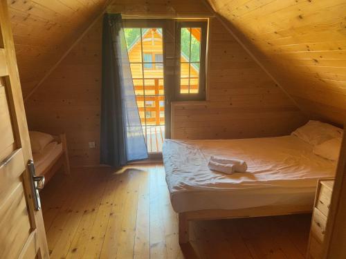 a bed in a wooden room with a window at Domki Letniczówka Kołobrzeg nad morzem in Grzybowo