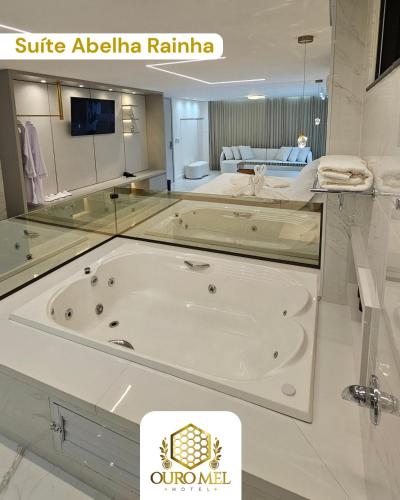 eine große weiße Badewanne in einem Zimmer mit einem Bett in der Unterkunft Hotel Ouro Mel in Santa Bárbara