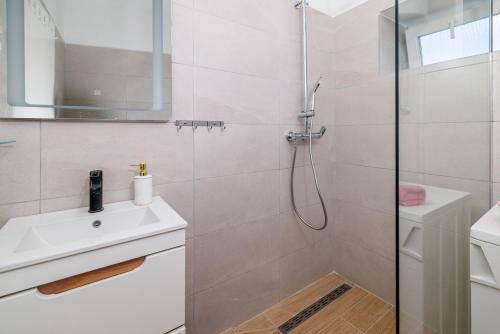 a white bathroom with a shower and a sink at House Katica in Grižane