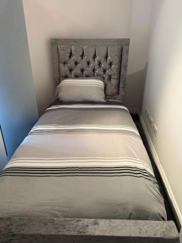 a bed in a small room with a large headboard at The City Glasgow in Glasgow