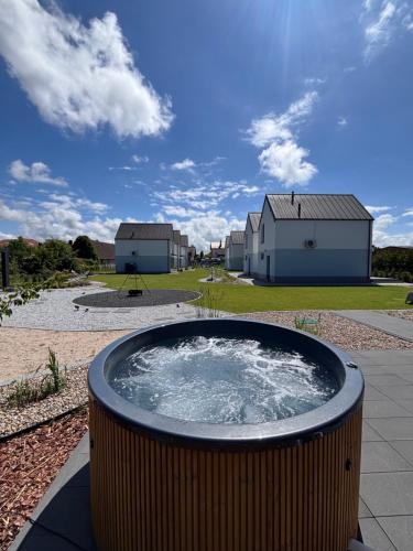 a hot tub in a yard with buildings in the background at Siedlisko na wydmach,domki klimatyzowane,starlink internet,parking in Łeba