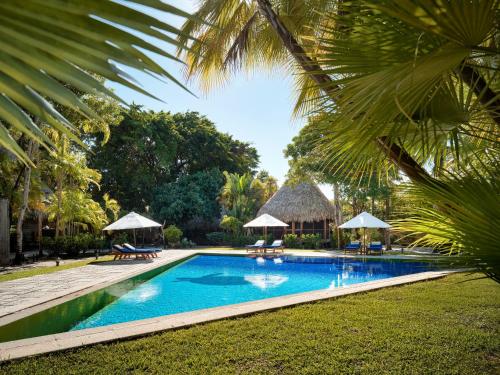 a pool with chairs and umbrellas next to a resort at Turtle Inn by Francis Ford Coppola in Placencia