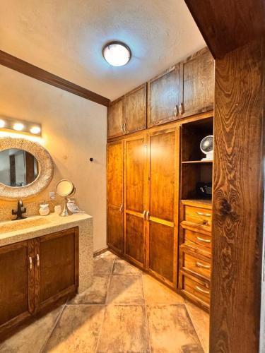 a bathroom with a sink and a mirror and wooden cabinets at Casa San Jerónimo Departamentos in Todos Santos