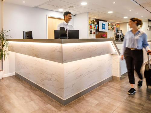 two people walking past a marble counter in a store at ibis budget Leicester in Leicester