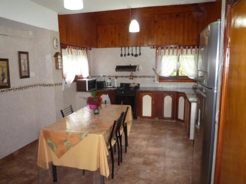 a kitchen with a table with chairs and a refrigerator at Chalet familiar adosado Rosas Rojas in Villa Gesell
