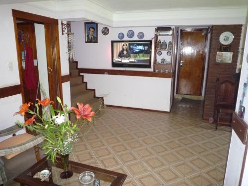una sala de estar con una escalera y un jarrón de flores en Chalet familiar adosado Rosas Rojas en Villa Gesell