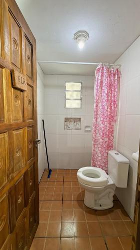 a bathroom with a toilet and a pink shower curtain at Casa temporada Ilha Comprida 350m da praia in Ilha Comprida