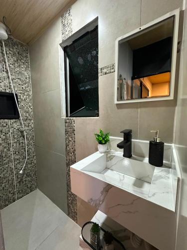 a bathroom with a white sink and a shower at Studio Aconchegante - com Garagem Privativa e Ar Condicionado REV391 in Joinville