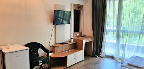 a room with a tv and a desk with a chair at Алюр студио Приморско - Studio Allure Primorsko in Primorsko