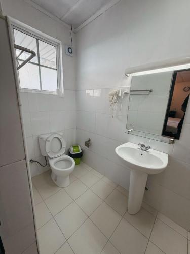 a white bathroom with a toilet and a sink at The Rock Hotel in Nuwara Eliya