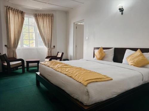 a bedroom with a large bed with a yellow blanket on it at The Rock Hotel in Nuwara Eliya