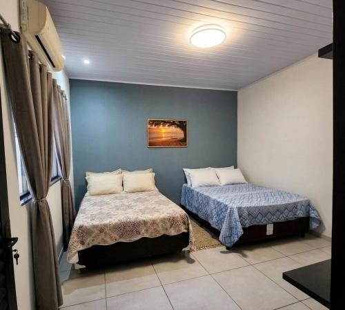 two beds in a room with blue walls at Espaço Manacá in Dourados