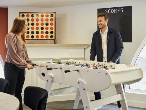 a man and a woman standing next to a foosball table at Aparthotel Adagio Monaco Palais Joséphine in Beausoleil
