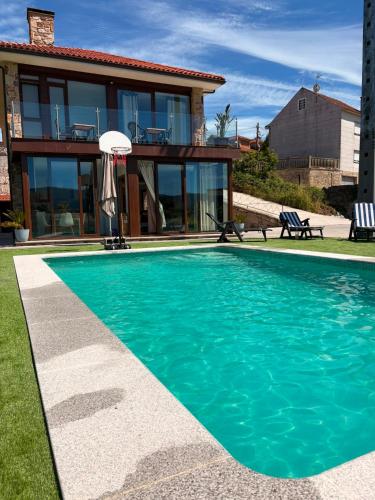 a swimming pool in front of a house at CESANTES VILLAGE e in Pontevedra