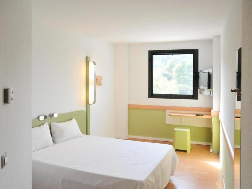 a hotel room with a white bed and a window at Ibis Budget Girona Costa Brava in Girona