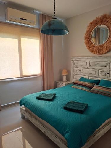 a bedroom with a bed with green sheets and a mirror at Sun Valley 2-bedroom apartment in Nicosia International Airport