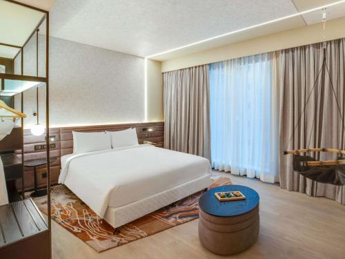 a bedroom with a white bed and a large window at Novotel Pune Viman Nagar Road in Pune