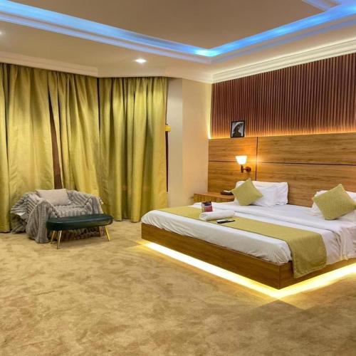 a hotel room with two beds and a chair at Brava Hotel in Ibadan