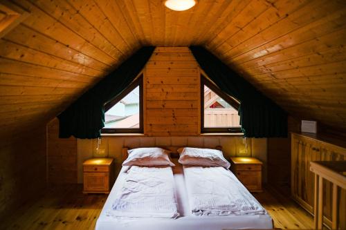 a bed in a wooden room with two windows at Domki u danusi in Stężyca