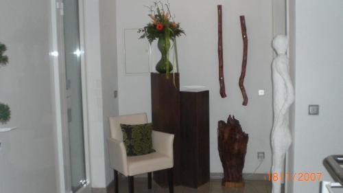 a living room with a chair and a vase with flowers at Hotel Villa Rosa in Allershausen