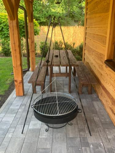 a grill on a patio with a picnic table and benches at Domek letniskowy Remix in Zwierzyniec