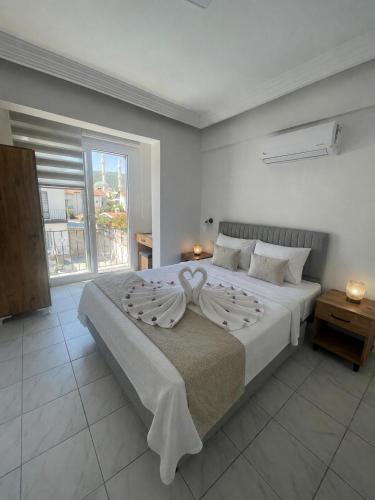 a white bedroom with a large bed and a window at çam otel in Fethiye