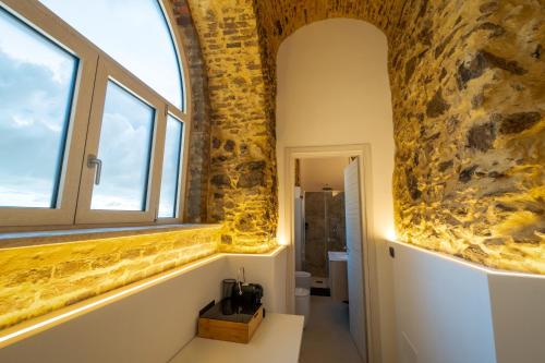a bathroom with a stone wall and a window at B&B Hipponion in Vibo Valentia