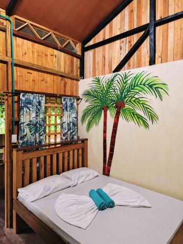 a bed in a room with a palm tree at La Orquídea Cabañas in Playa Ladrilleros