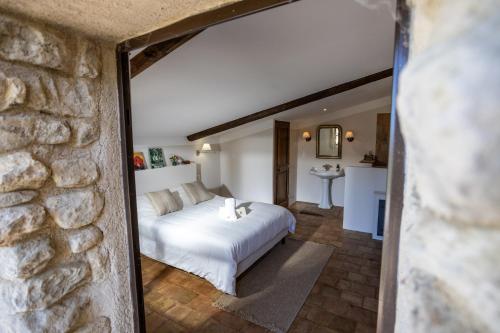 a bedroom with a white bed and a stone wall at Maison Roque in Sannes