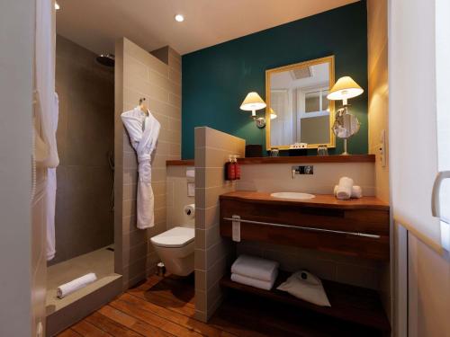 a bathroom with a sink and a toilet and a mirror at Royal Emeraude Hotel Dinard - MGallery Collection in Dinard
