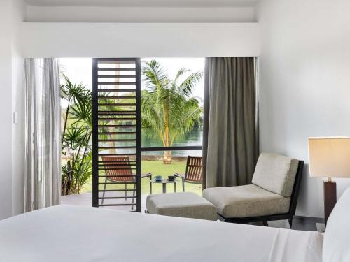 a bedroom with a bed and a chair and a window at Novotel Suva Lami Bay in Suva