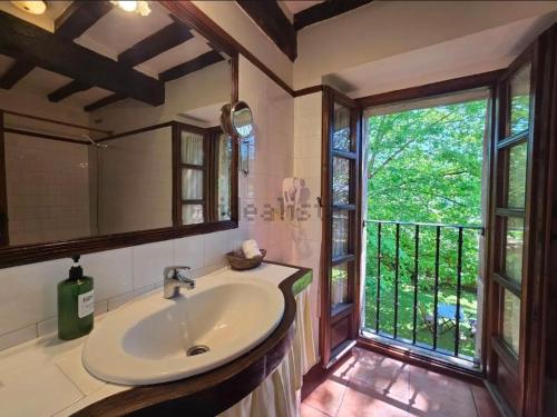 a bathroom with a sink and a large window at Casona De La Salceda in Treceño
