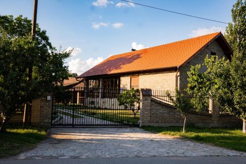 a brick house with an orange roof and a gate at Rodjino imanje in Palić