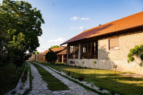 a brick building with a stone path next to a house at Rodjino imanje in Palić