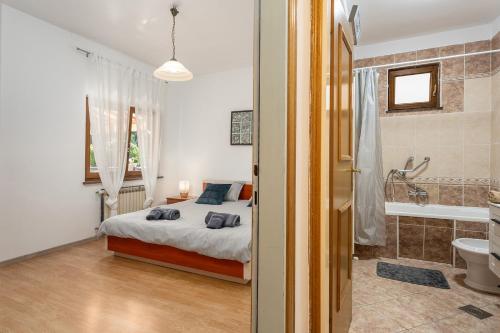 a bedroom with a bed and a bathroom with a tub at Apartman Noemi in Kukci