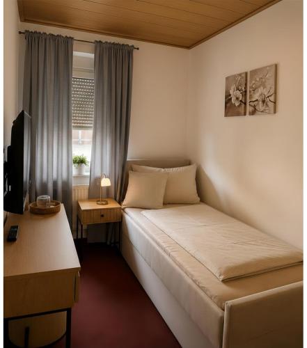a bedroom with a bed and a desk and a window at Pension Glück in Schleife