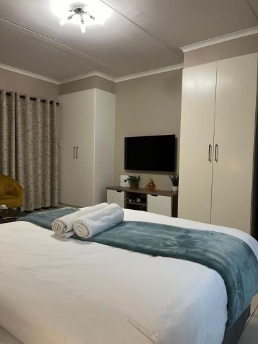 a bedroom with a large bed with a flat screen tv at Dainfern Cozy Loft in Fourways