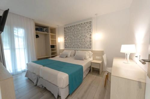 a bedroom with a large bed with a blue blanket at hotel apartamento es Talaial in Cala d´Or