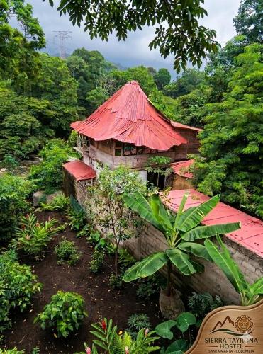an old building with a red roof in a forest at Sierra Tayrona hostel in El Zaino