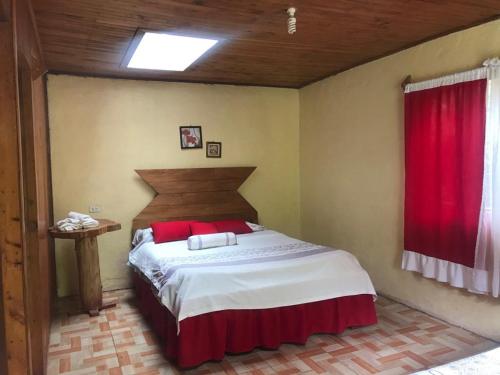 a bedroom with a large bed with a red curtain at Lagunillas Del Poas in Poasito