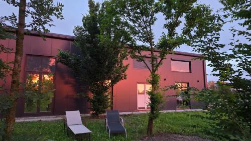 a red house with two chairs in front of it at Hangar Hangout by the Lake in Priles