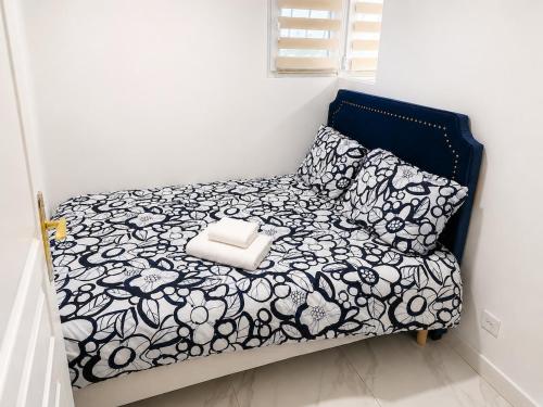 a bed with a black and white blanket and pillows at EDEN SUITE Escale proche de CDG in Tremblay-En-France