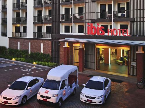 two white cars parked in a parking lot in front of a building at Ibis Phuket Kata in Kata Beach