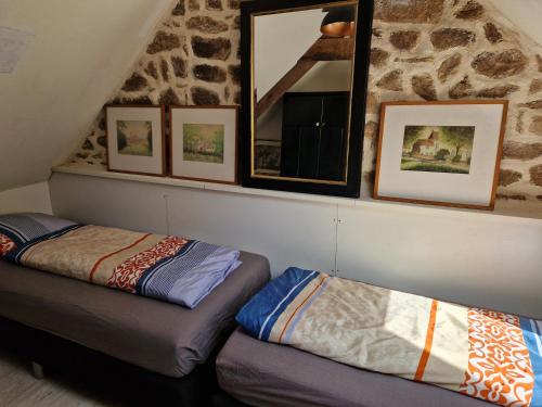 a attic room with two beds and pictures on the wall at Gites Armorique in Plésidy