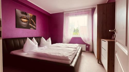 a bedroom with a bed with purple walls and a window at Apartment Am Paradies in Bad Lauterberg