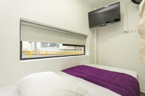 a bedroom with a bed with a window and a tv at Hotel Zona Express San Diego in Medellín