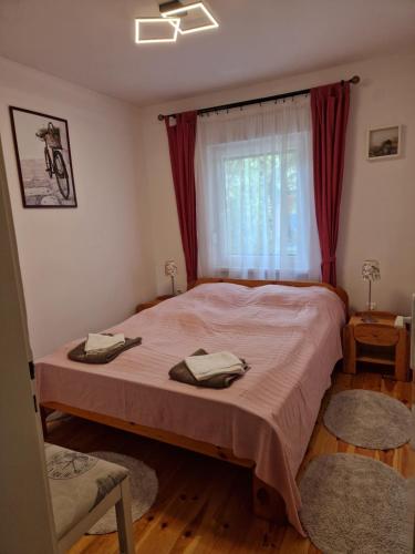 a bedroom with a bed and a window with red curtains at Nefelejcs-el vendeghaz in Balatonmáriafürdő