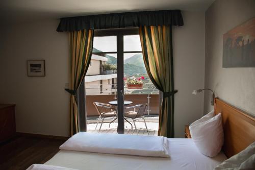 a hotel room with a bed and a view of a balcony at Hotel Tannerhof in Schenna