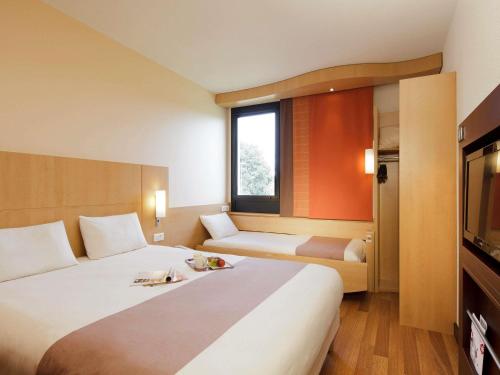 a hotel room with a large bed and a television at Hôtel ibis Guingamp Cœur de Bretagne in Ploumagoar